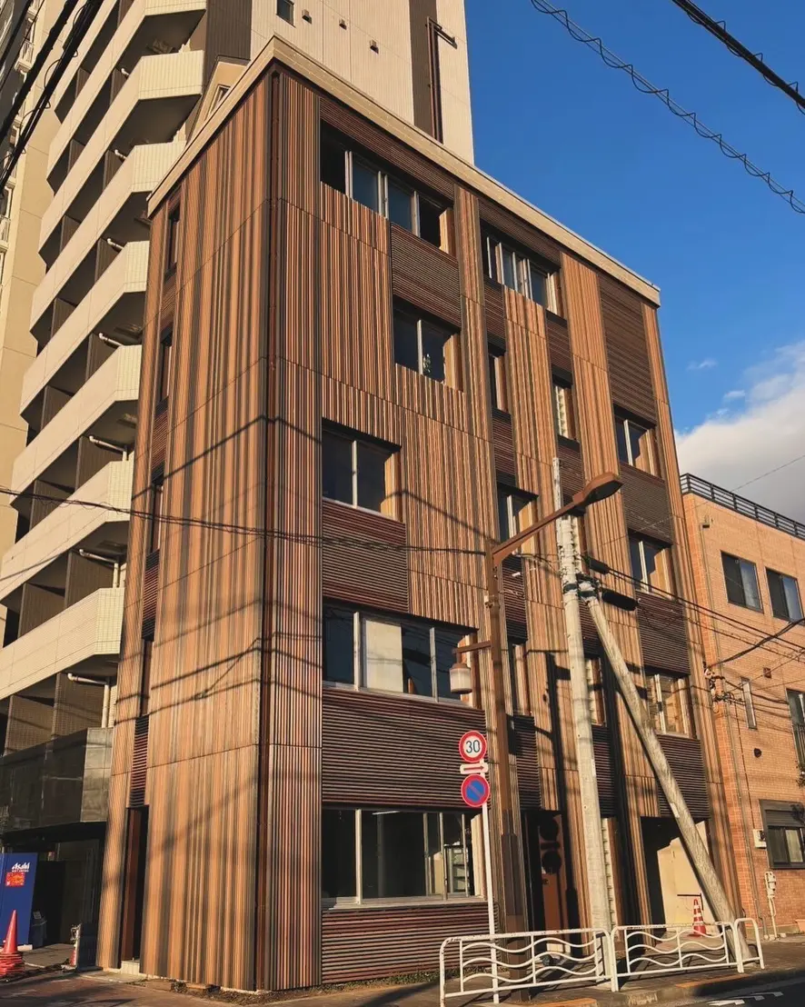 木製の縦ルーバーで外壁を覆った5階建てビルの外観
