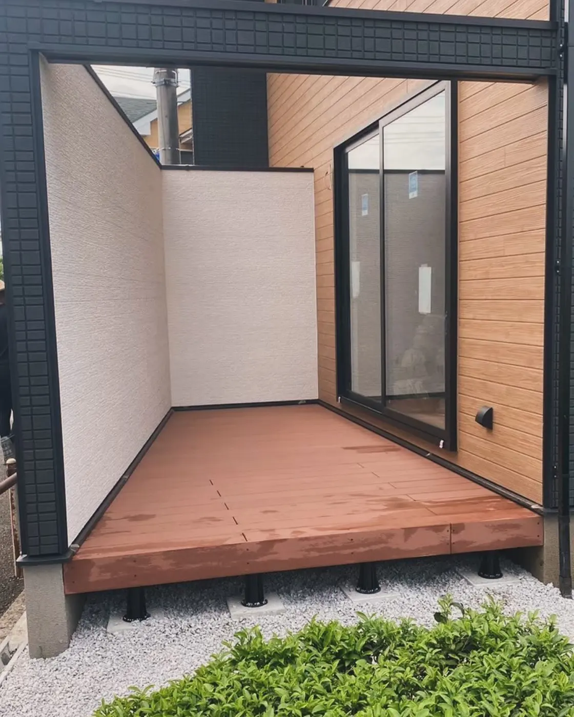 中庭の掃き出し窓の前に納めた赤褐色の人工木デッキ